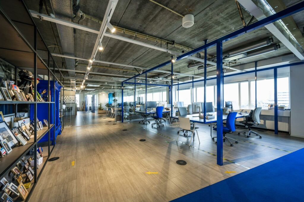 Modern en licht kantoorinterieur aan de Johan Huizingalaan met open werkplekken, industriële plafonds en persoonlijke fotodisplay.